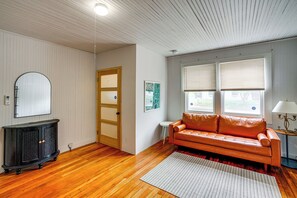 A room with wooden flooring, a sofa, a cabinet, a door, and windows with blinds. - Walk to Everything! Dtwn Hudson Apartment (Hudson)