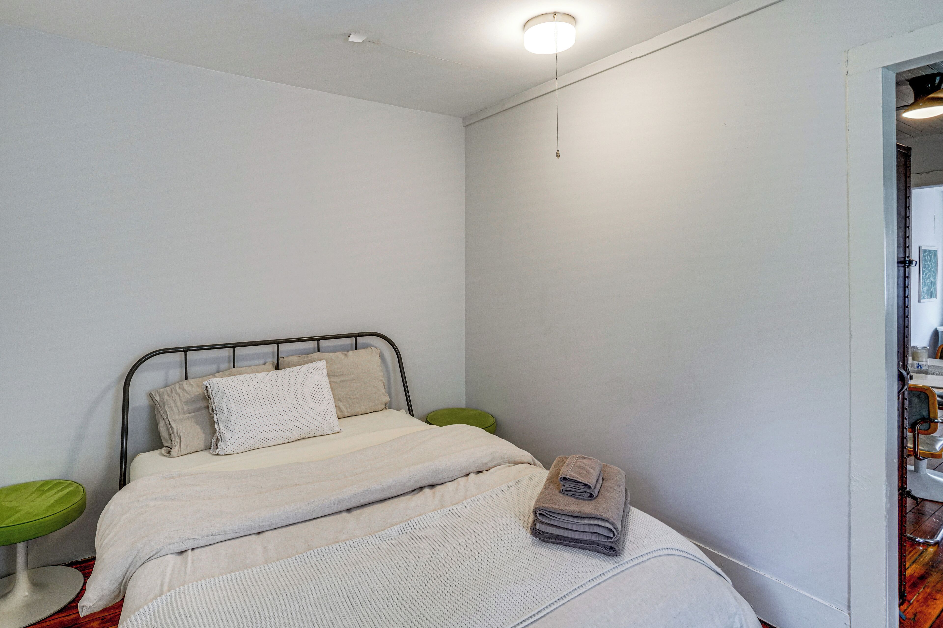 Une chambre à coucher avec un lit, une table de chevet verte et une porte donnant sur une salle de bain.
