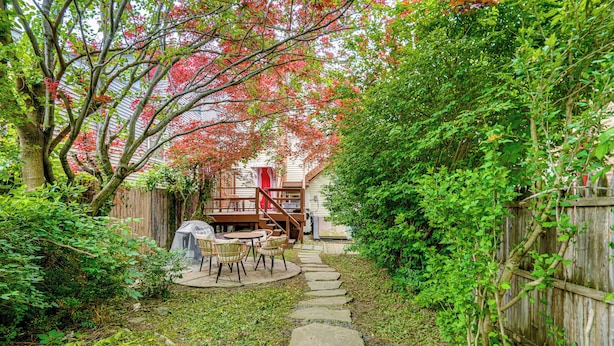 A garden with a stone path leading to a wooden deck with outdoor furniture. - Walk to Everything! Dtwn Hudson Apartment (Hudson)