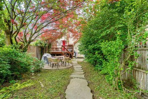 A garden with a stone path leading to a wooden deck with outdoor furniture. - Walk to Everything! Dtwn Hudson Apartment (Hudson)