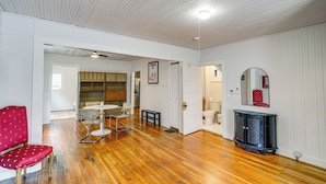 A room with wooden flooring, a red chair, a small table, a mirror, and a cabinet. - Walk to Everything! Dtwn Hudson Apartment (Hudson)