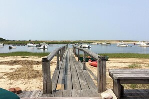 A wooden pier leading to a calm water body with boats docked. - Waterfront Studio w/ Dock & Beach Access in Truro! (Truro)