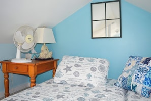 A bedroom with a bed, a nightstand with a lamp and fan, a dresser, and a window. - Waterfront Studio w/ Dock & Beach Access in Truro! (Truro)
