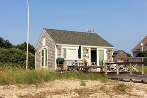 A beach house with a wooden deck, outdoor furniture, and a green door. - Waterfront Studio w/ Dock & Beach Access in Truro! (Truro)