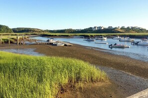 A calm waterfront with boats docked, grassy banks, and a clear sky. - Waterfront Studio w/ Dock & Beach Access in Truro! (Truro)