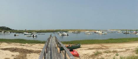 A wooden pier leading to a calm body of water with boats docked.