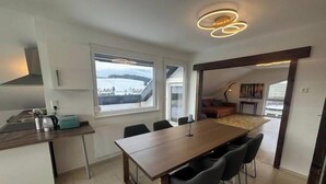 A modern kitchen with a large window, a dining area with a table and chairs, and a view of a snowy landscape. - Vacation apartment Schwarzwaldblick Unterkirnach (Unterkirnach)
