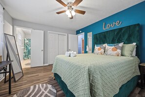 A bedroom with a bed, a ceiling fan, a wall with the word 'Love,' and a door leading to another room. - Easy ATL Access! Suburban Retreat w/ Yard & Patio (Riverdale)