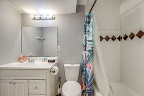 A bathroom with a white sink, mirror, toilet, and shower curtain. - Easy ATL Access! Suburban Retreat w/ Yard & Patio (Riverdale)