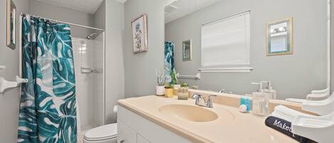 Un baño con ducha, inodoro, lavabo y espejo.
