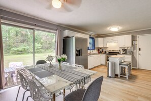 A modern kitchen with white cabinets, a stainless steel refrigerator, and a dining area with a glass table and chairs. - Easy ATL Access! Suburban Retreat w/ Yard & Patio (Riverdale)