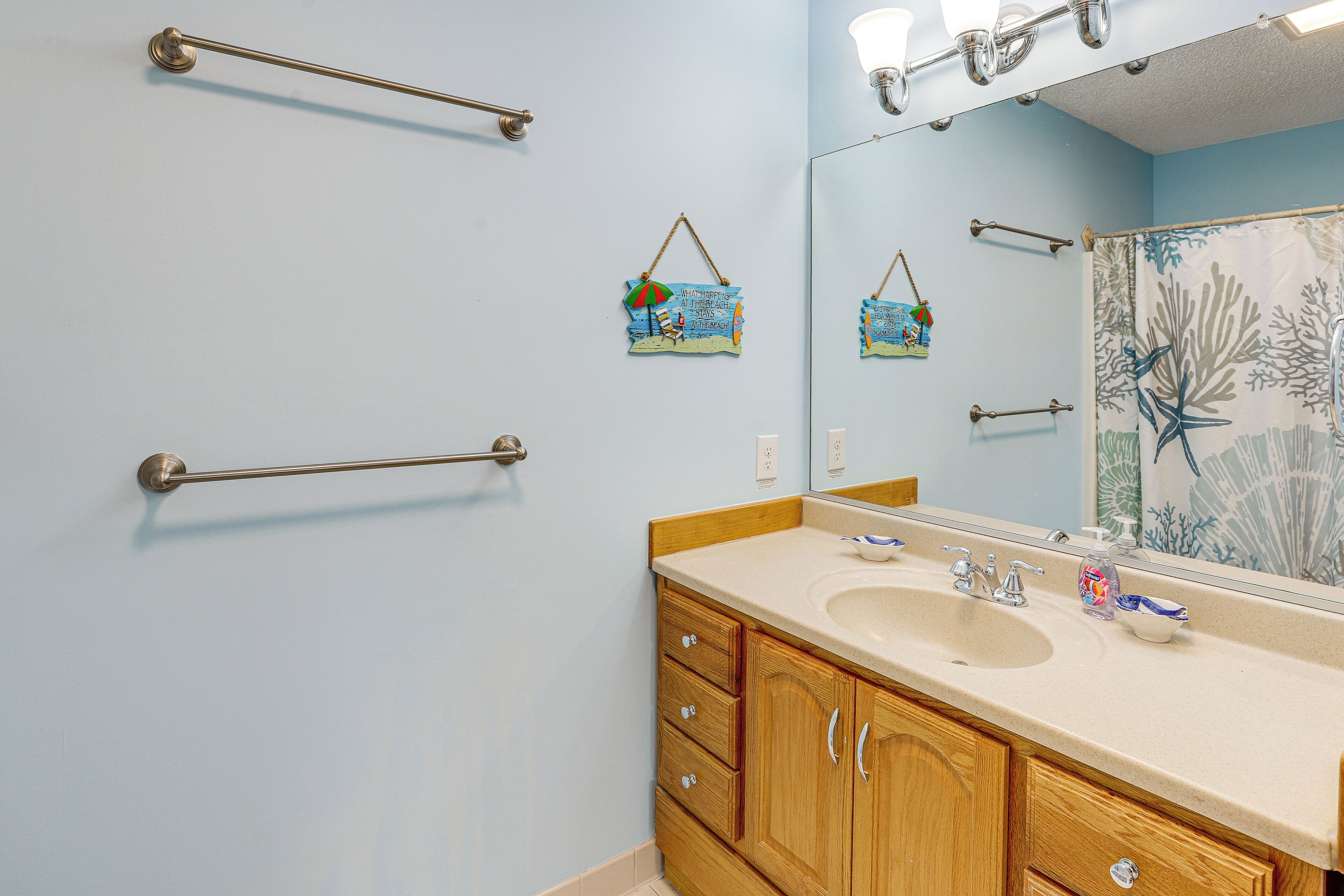 Un baño con lavabo, espejo, toallero y detalles decorativos.