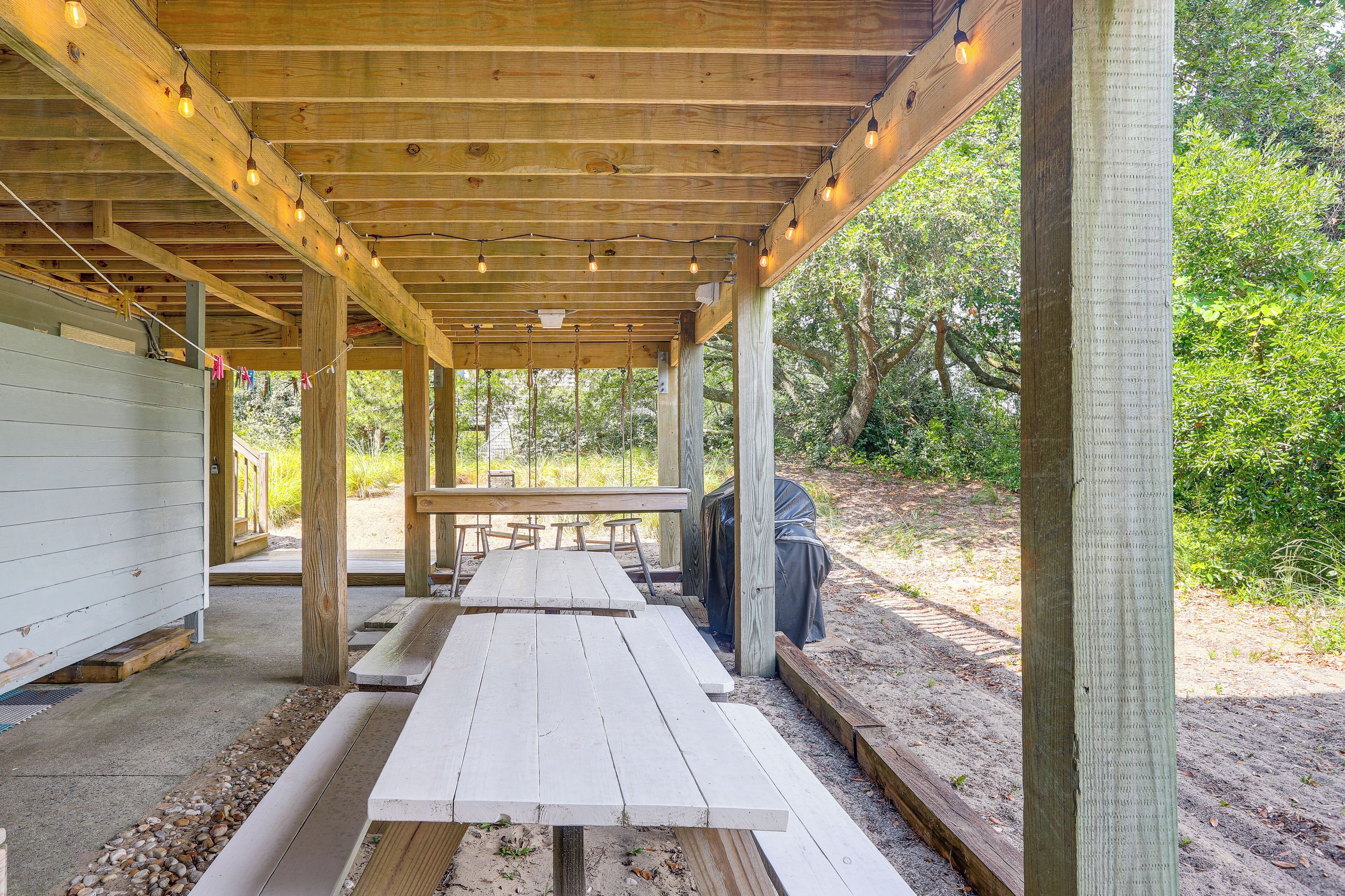 A covered outdoor dining area with picnic tables and string lights.