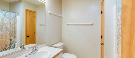 Un baño con lavamanos, espejo, inodoro y cortina de ducha.