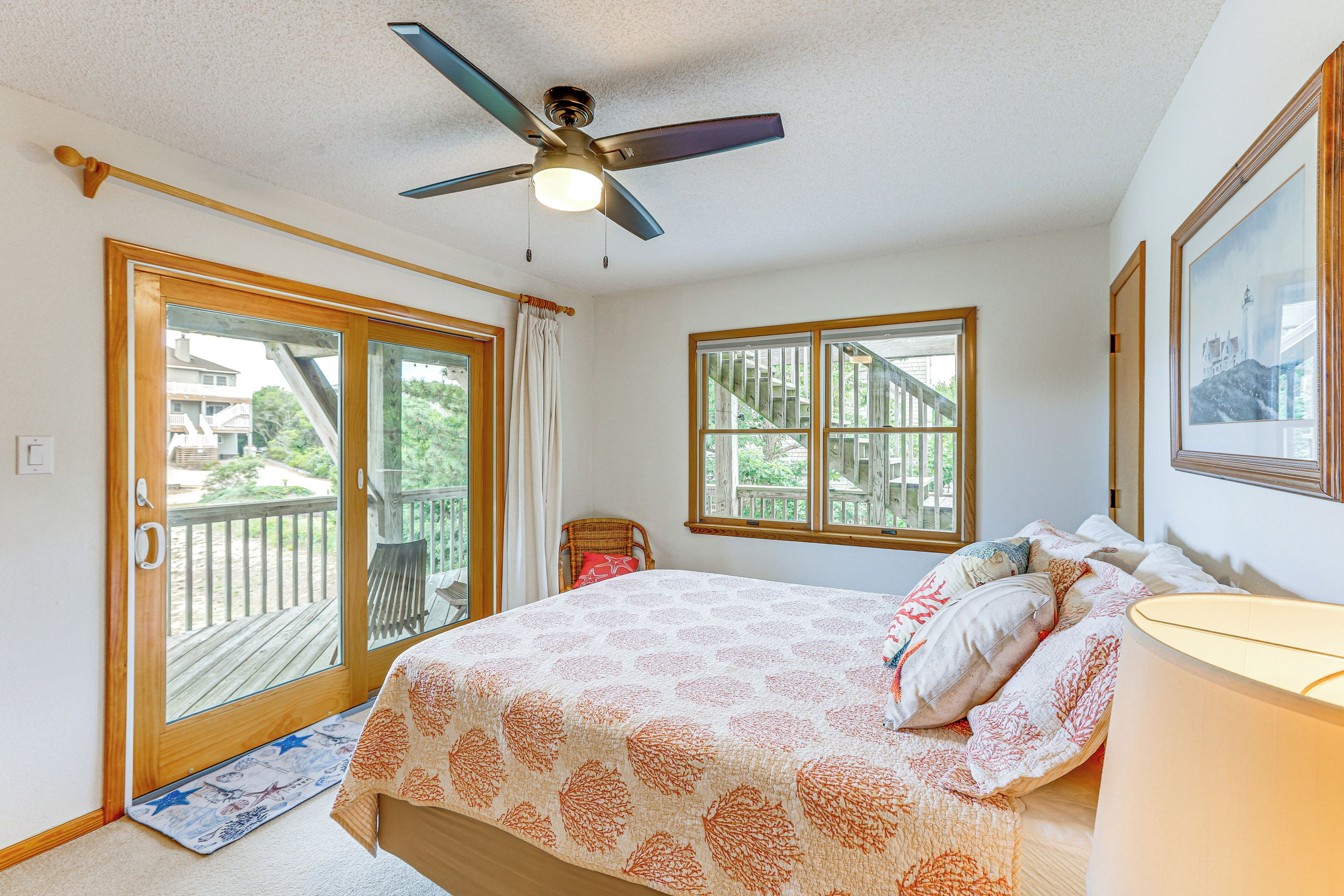 A bedroom with a bed, a ceiling fan, a window, and a door leading to an outdoor area.