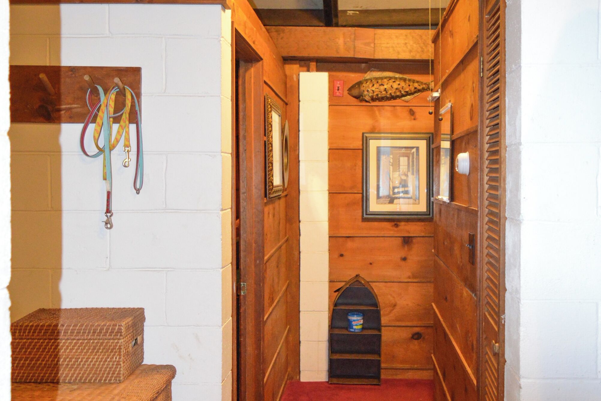 A narrow hallway with wooden walls, a white door, and a small wooden shelf with a can.