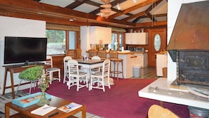 A living room with a television, dining area, kitchen, and fireplace.