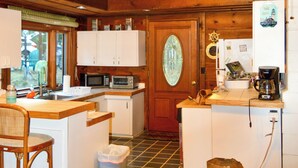 A compact kitchen with white cabinets, a microwave, a coffee maker, and a wooden door with a glass window.