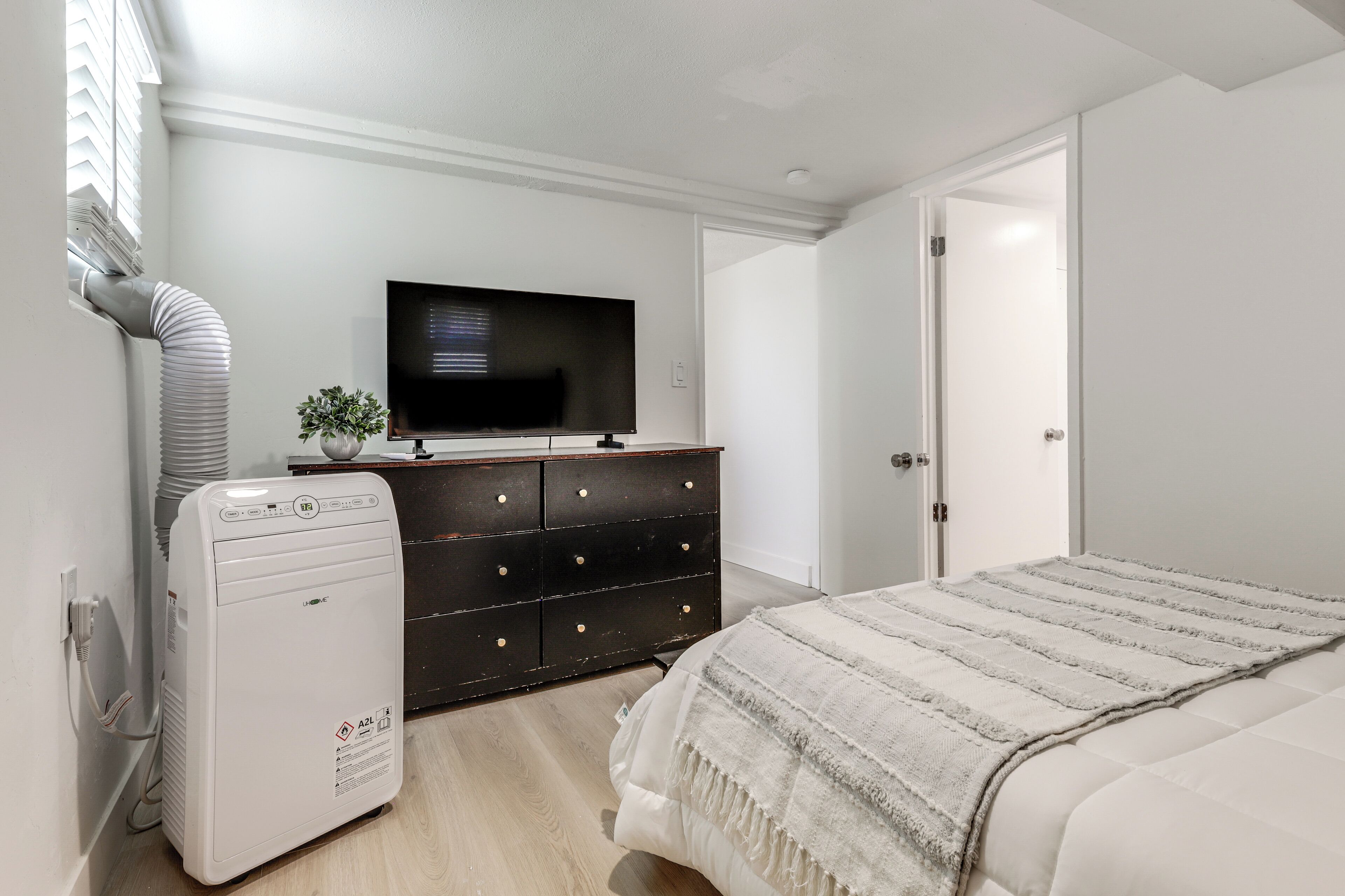 A bedroom with a bed, a TV, a dresser, and a heater.