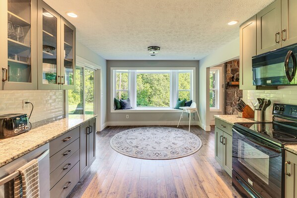 Una cocina con estufa integrada, un rincón con asiento junto a la ventana y vistas al exterior.