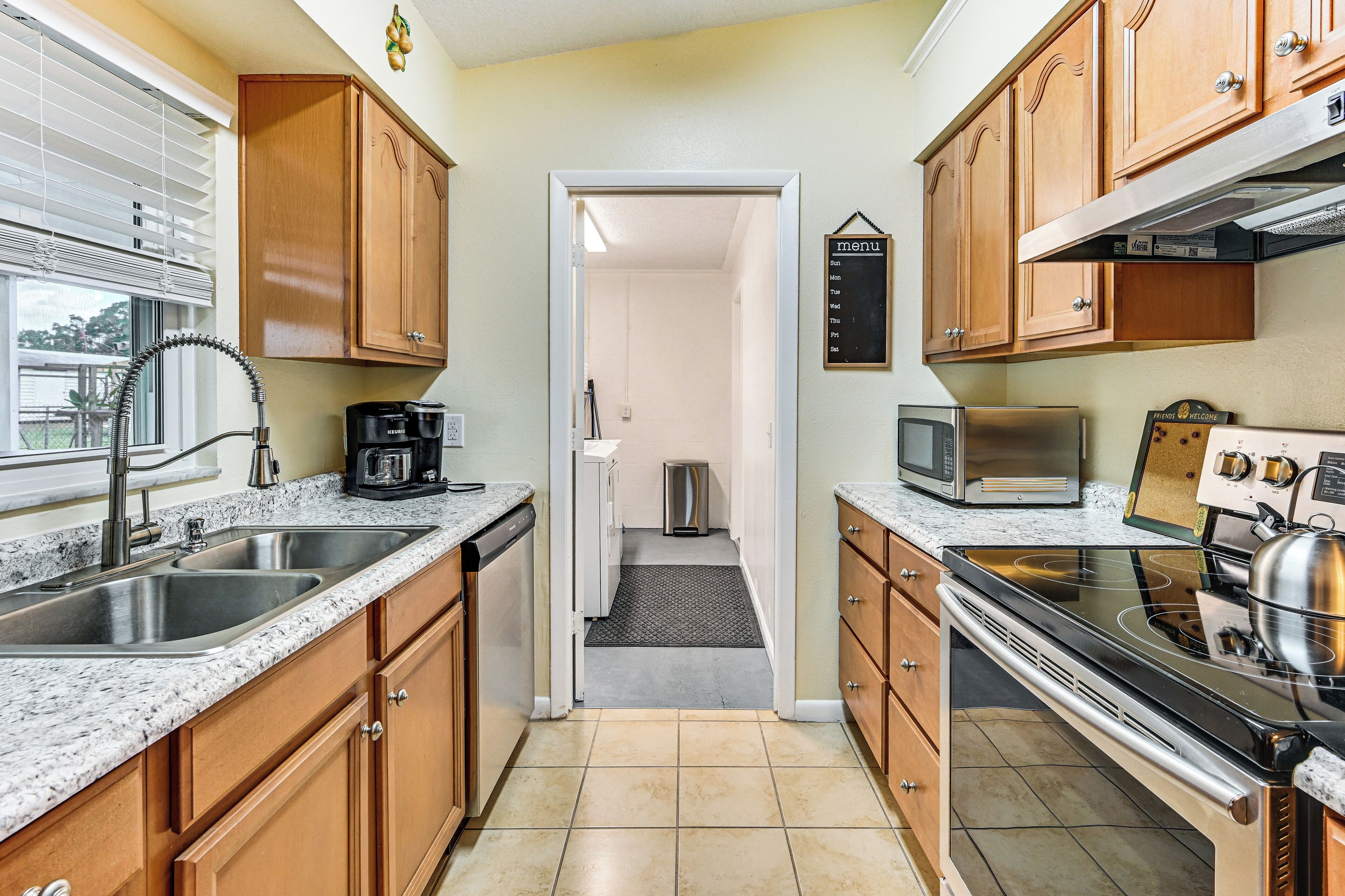 A kitchen with wooden cabinets, a stainless steel sink, a microwave, and a stove.