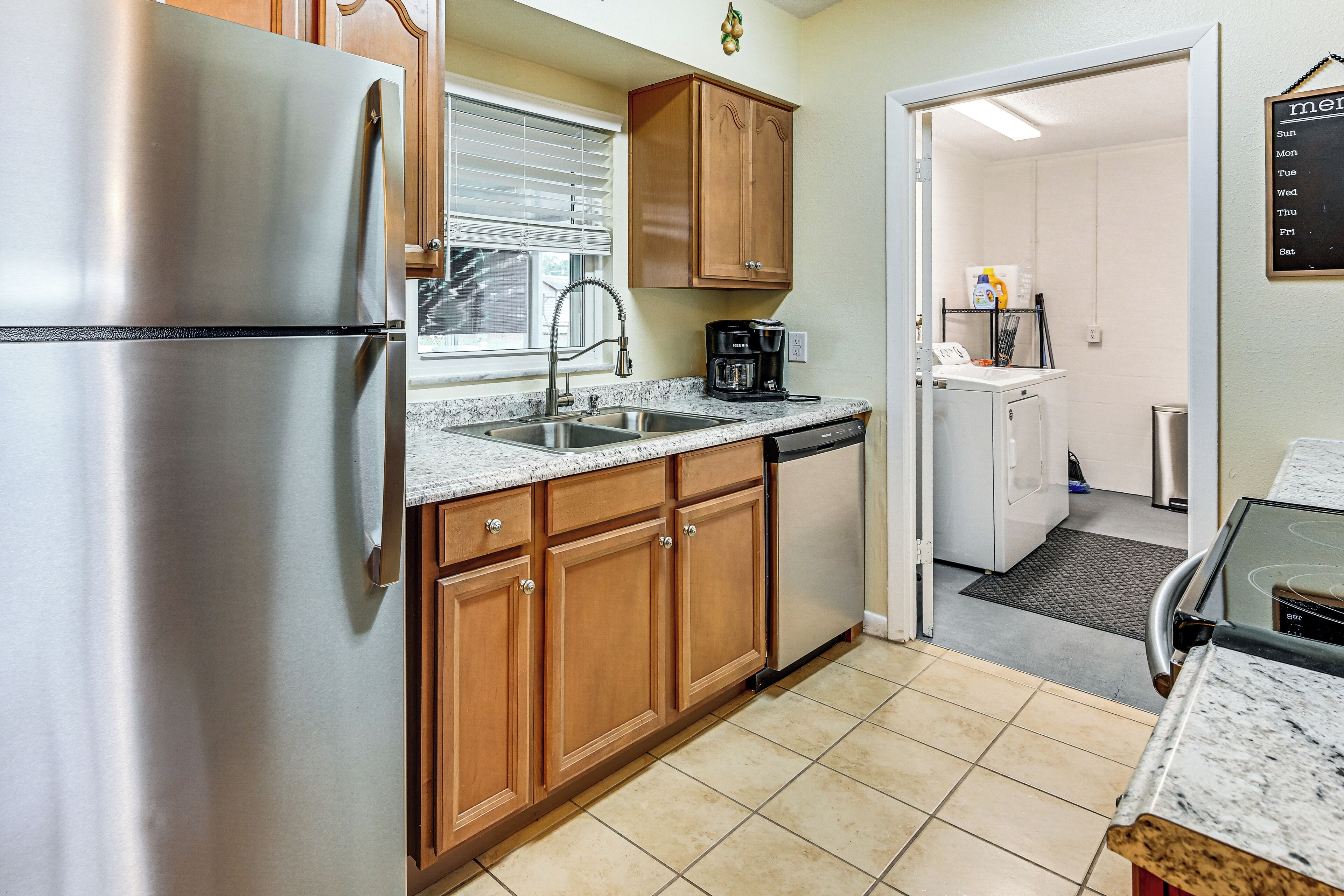 A kitchen with stainless steel appliances, wooden cabinets, a coffee maker, and a dishwasher.