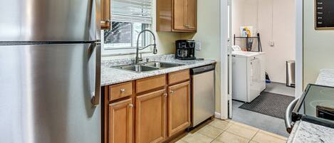 A kitchen with stainless steel appliances, wooden cabinets, a coffee maker, and a dishwasher.