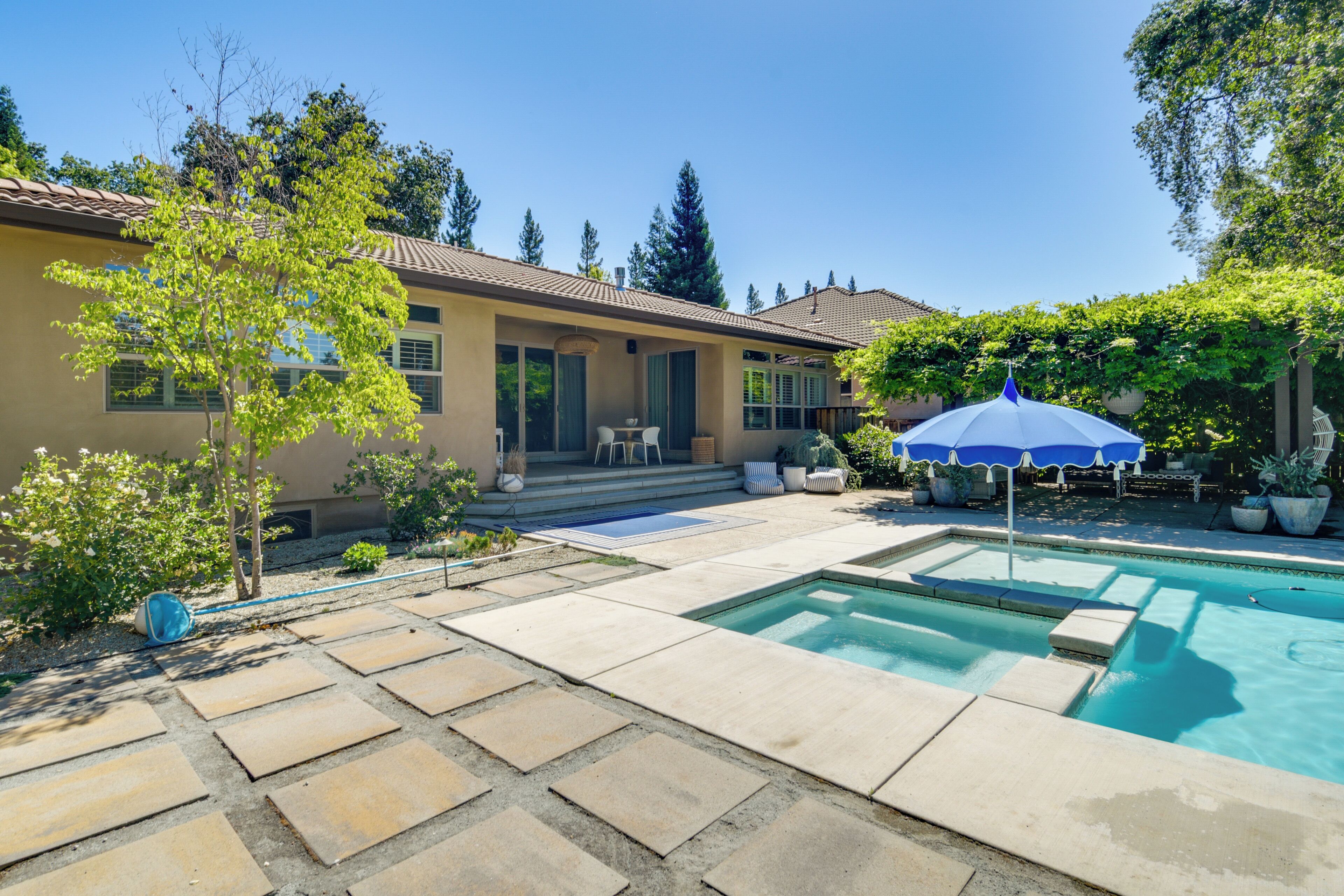 A backyard with a swimming pool, patio furniture, and a house.