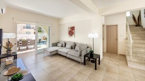 Ein Wohnzimmer mit Ecksofa, Glastür zum Balkon, Treppe und Flachbildfernseher.