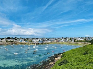 A coastal town with boats in the water and houses along the shore. - Granite house by Portsall fishing port in Brittany (Ploudalmezeau)