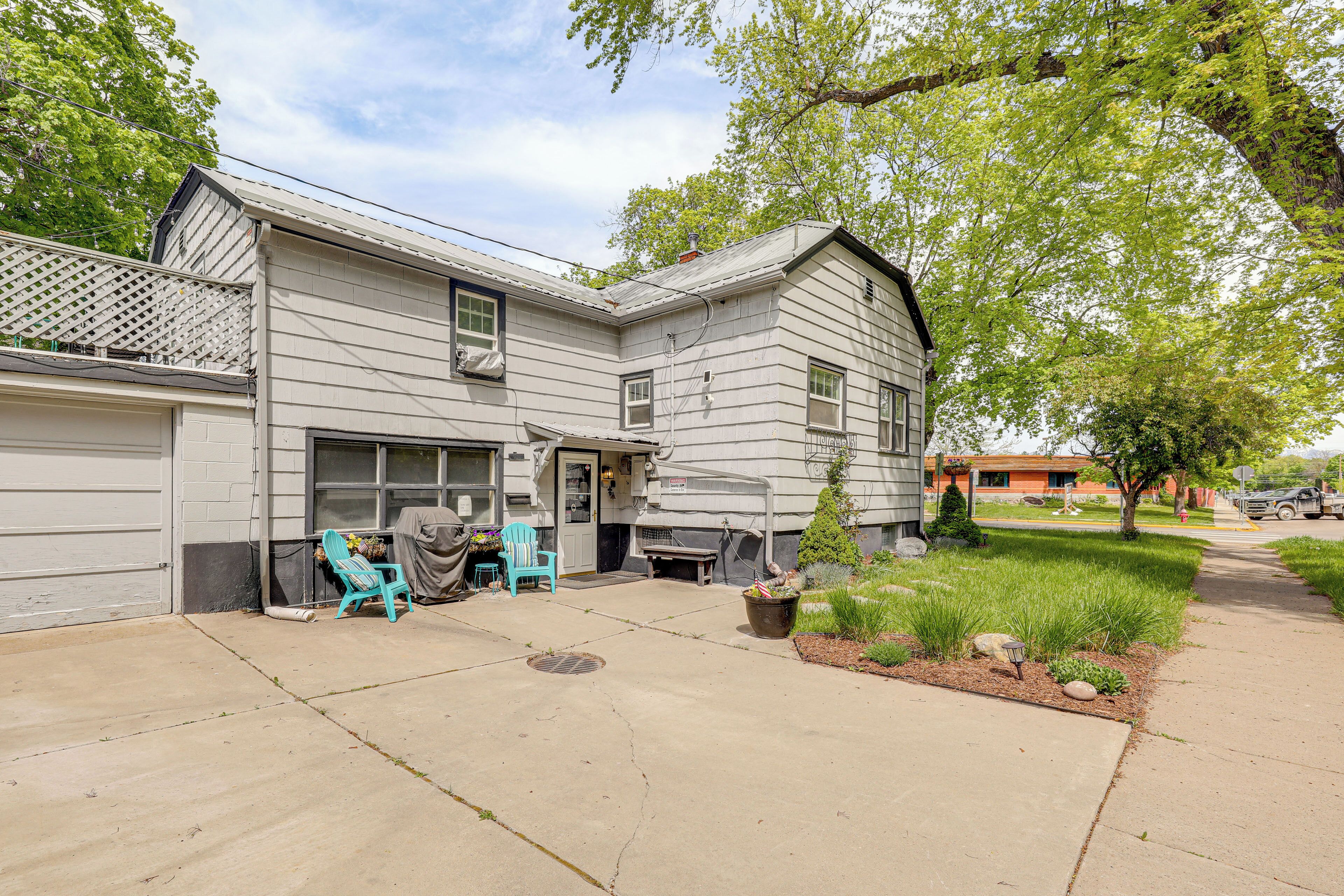 A two-story house with a garage, a covered patio, and a small front yard with a lawn and a tree.