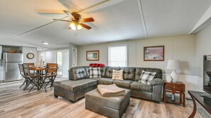A spacious living room with a sectional sofa, a dining table with chairs, a ceiling fan, and a kitchen area in the background. - Countryside Escape w/ Fire Pit By Mammoth Cave! (Brownsville)