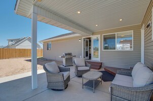Un patio exterior con mobiliario de mimbre, una parrilla y un área cubierta con vista a casas vecinas.
