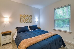 Un dormitorio con una cama, mesitas de noche, apliques de pared, una ventana con persianas y una obra de arte colgada en la pared.