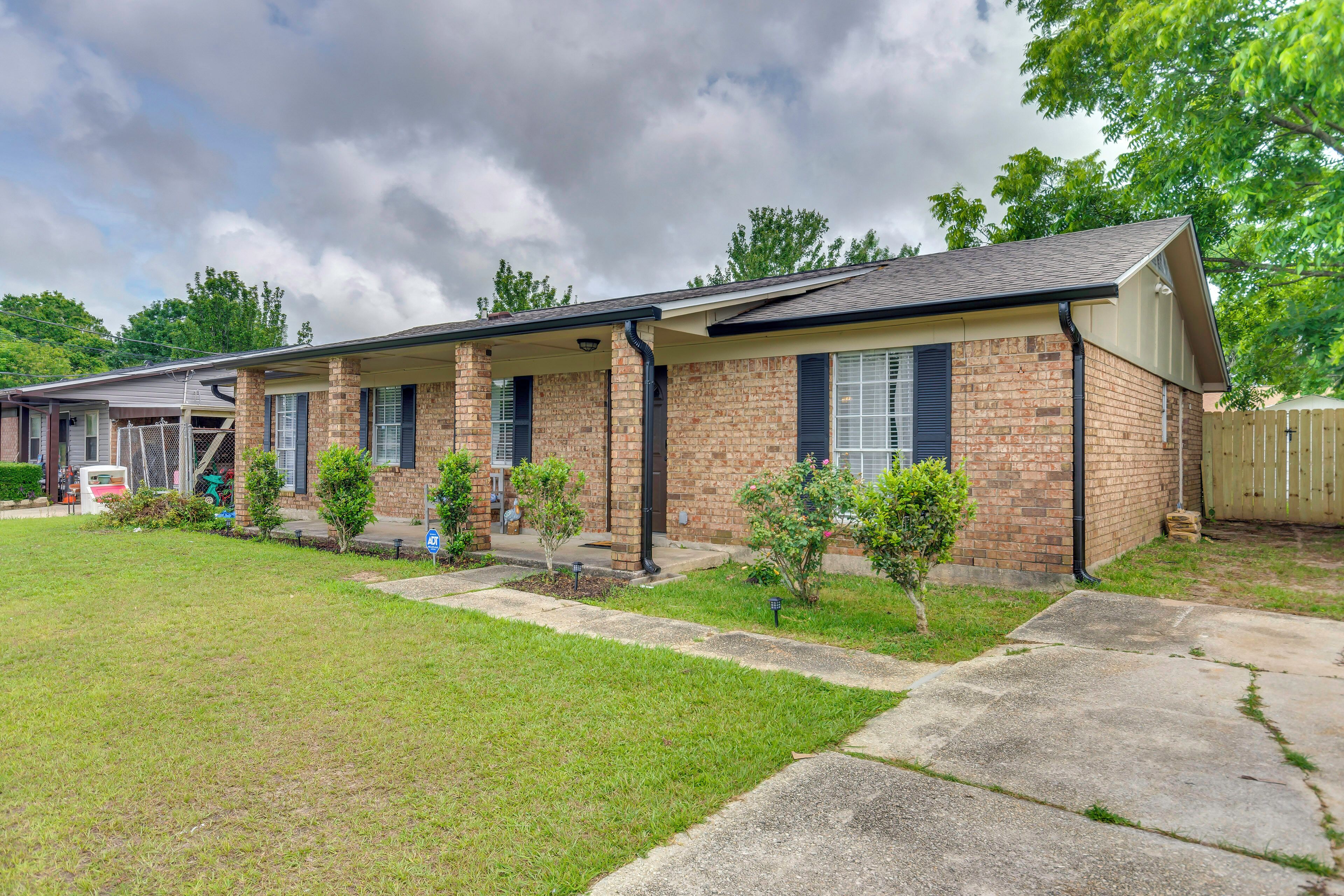 En tvåvåningsbyggnad i tegel med en inglasad veranda, små träd och en gräsplätt.