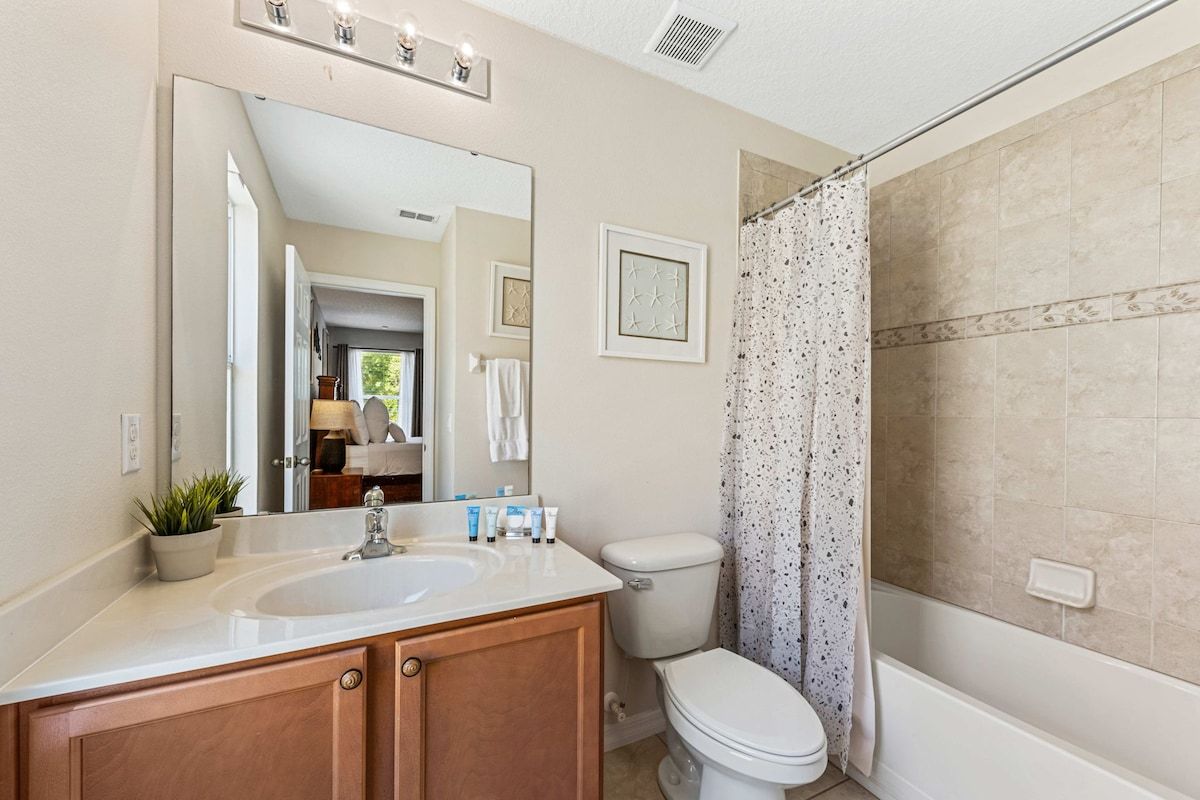 A bathroom with a sink, toilet, and shower curtain.