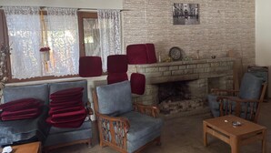 Uma sala de estar com lareira, um sofá, poltronas e uma mesa de centro.