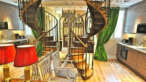 Una cocina moderna con una escalera espiral, suelo de madera y un comedor con mesa y sillas.