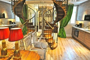 A modern kitchen with a spiral staircase, wooden flooring, and a dining area with a table and chairs. - Un Balcon sur Notre - Dame, Severine — AC (Paris)