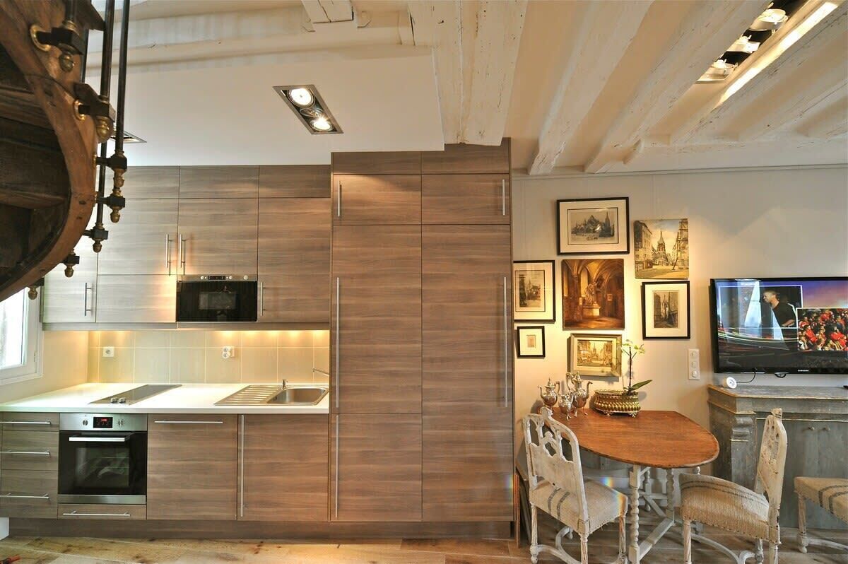 Eine moderne Küche mit Edelstahlgeräten, Holzschränken und einem Essbereich mit Holztisch und Stühlen.