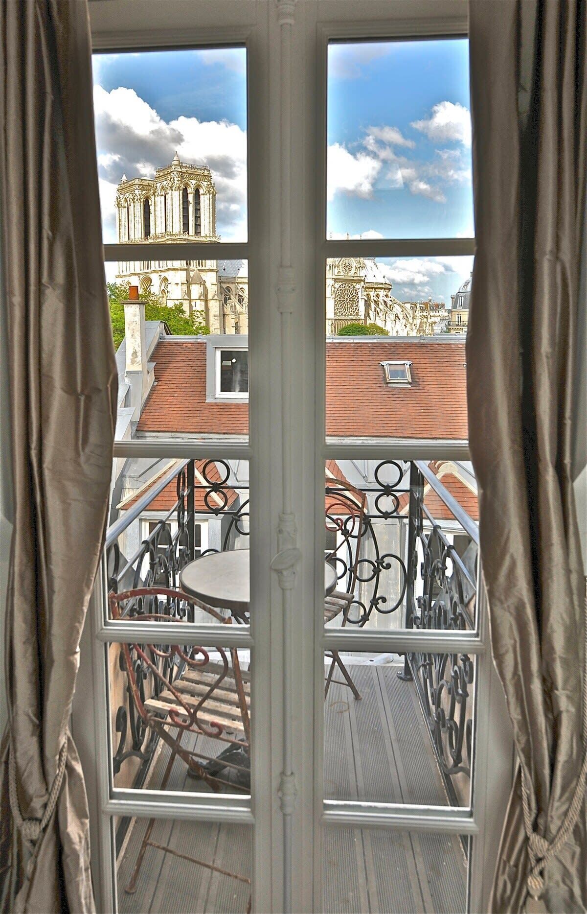 Ein Balkon mit Metallgeländern und einem Tisch, mit Blick auf ein historisches Gebäude mit aufwendiger Architektur.