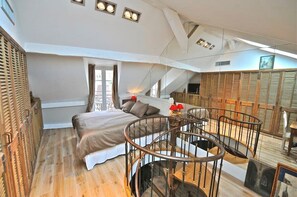 A bedroom with a bed, a circular staircase, and a view of the outside. - Un Balcon sur Notre - Dame, Severine — AC (Paris)