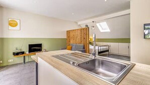 A modern kitchen with a built-in sink, a wooden panel wall, and a flat-screen TV. - Studio with terrace between Liège and Maastricht (Juprelle)