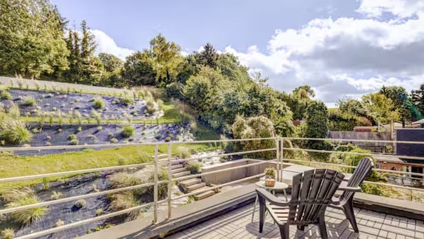 A rooftop terrace with a view of a landscaped area, outdoor seating, and a railing. - Studio with terrace between Liège and Maastricht (Juprelle)