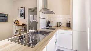 A modern kitchen with a stainless steel sink, a kettle, and a built-in oven. - Studio with terrace between Liège and Maastricht (Juprelle)