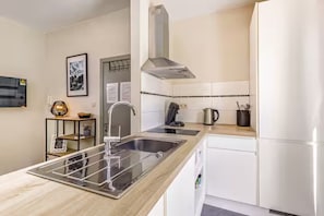 A modern kitchen with a stainless steel sink, a kettle, and a built-in oven. - Studio with terrace between Liège and Maastricht (Juprelle)