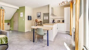 A modern kitchen with a central island, a dining area with chairs, and a view of the living room. - Studio with terrace between Liège and Maastricht (Juprelle)