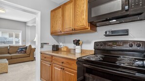 A kitchen with wooden cabinets, a black stove, and a microwave. - 404 Doc Susie home Delightful and renovated home, walk to downtown, mt views (Fraser)