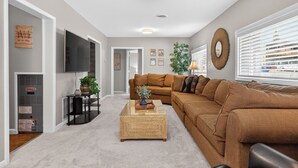 A living room with a sofa, a coffee table, a TV, and a plant. - 404 Doc Susie home Delightful and renovated home, walk to downtown, mt views (Fraser)