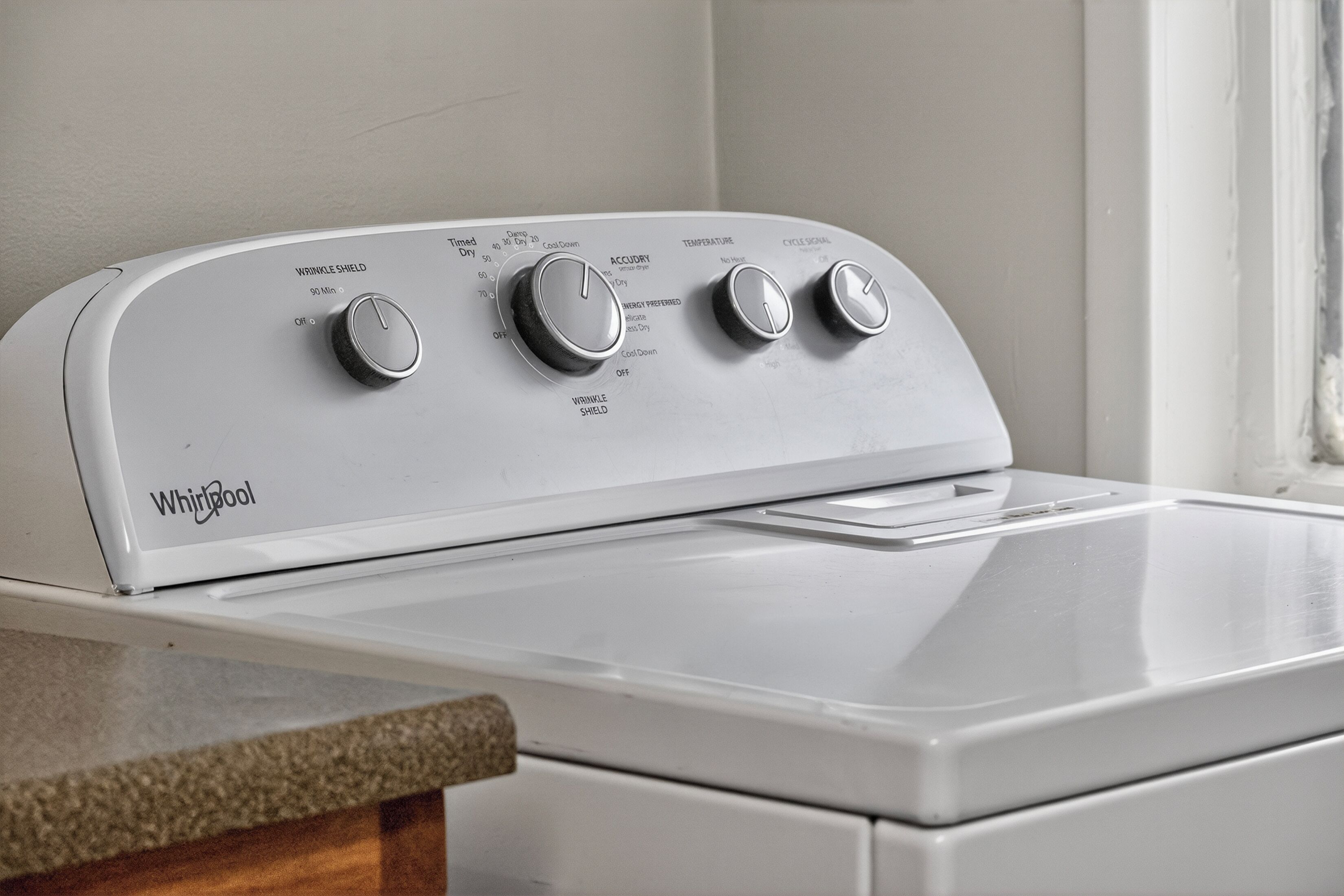 Een Whirlpool wasmachine met drie bedieningsknoppen, een timer en een temperatuurinstelling.